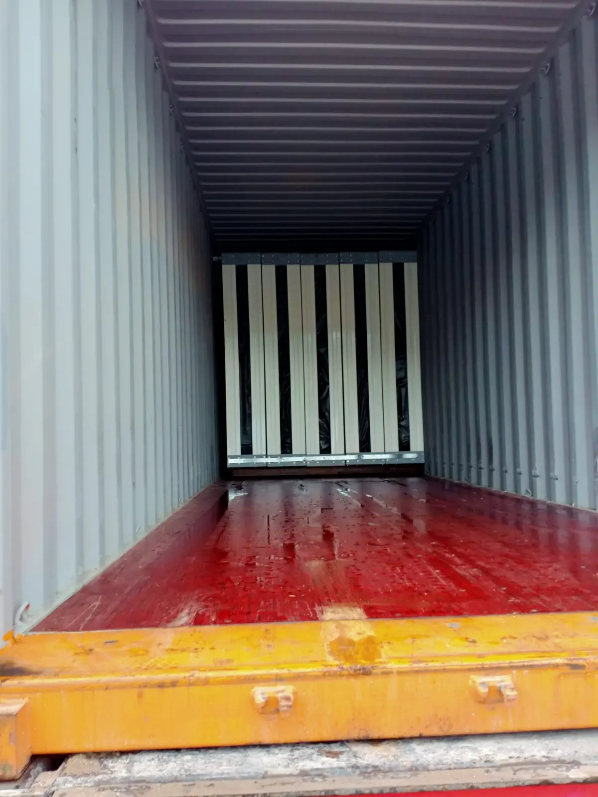 Flat-pack modular wall panels loaded inside an export shipping container