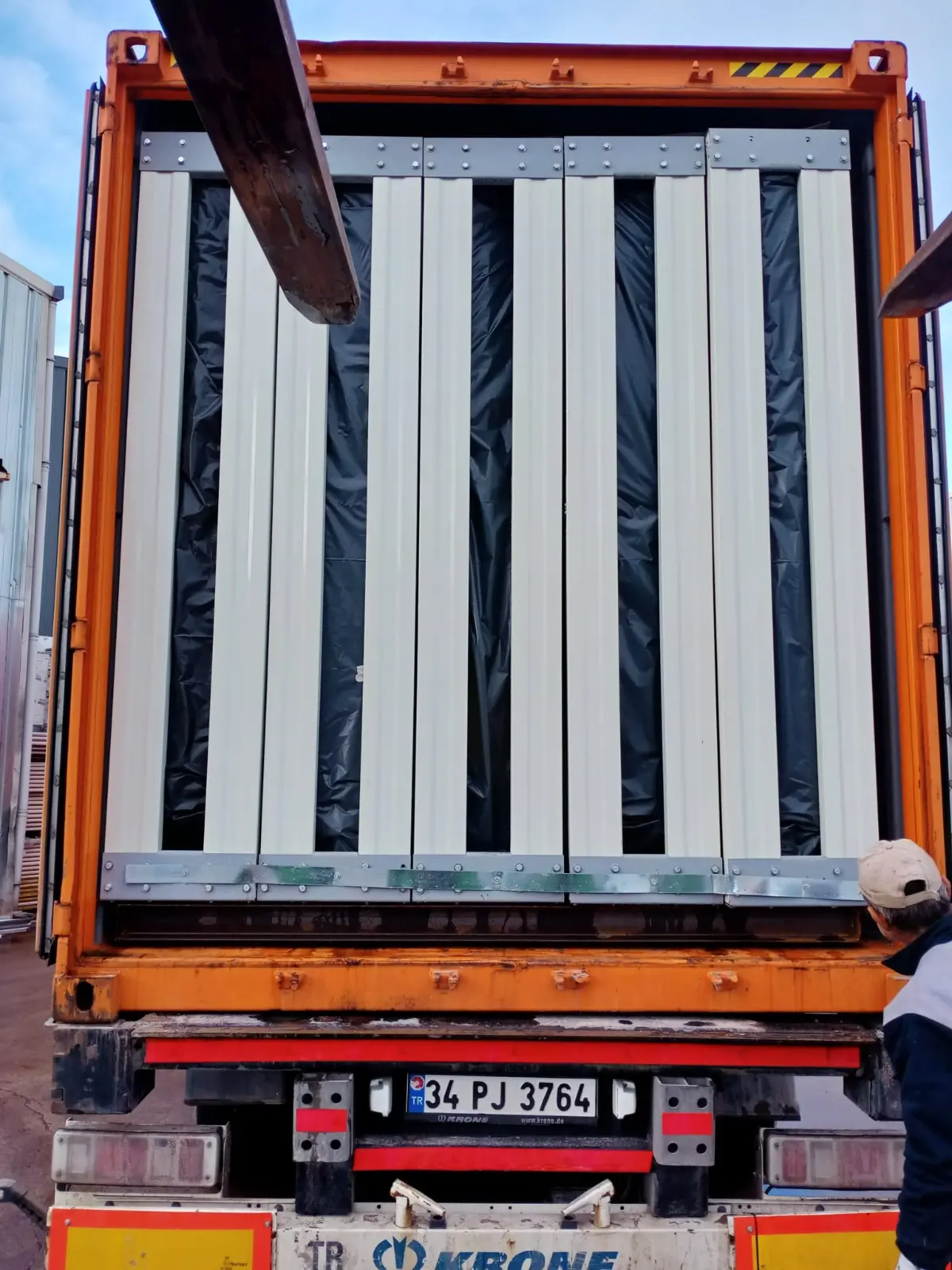 Flat-pack wall panels secured vertically inside a road trailer for export delivery