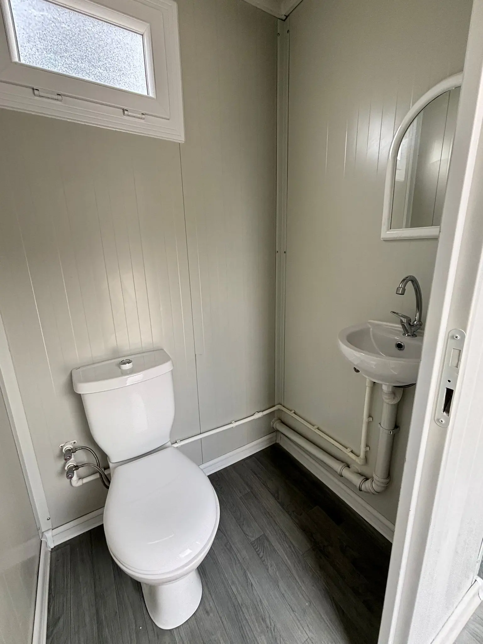 Compact completed modular WC cabin with washbasin, window and exposed service connections