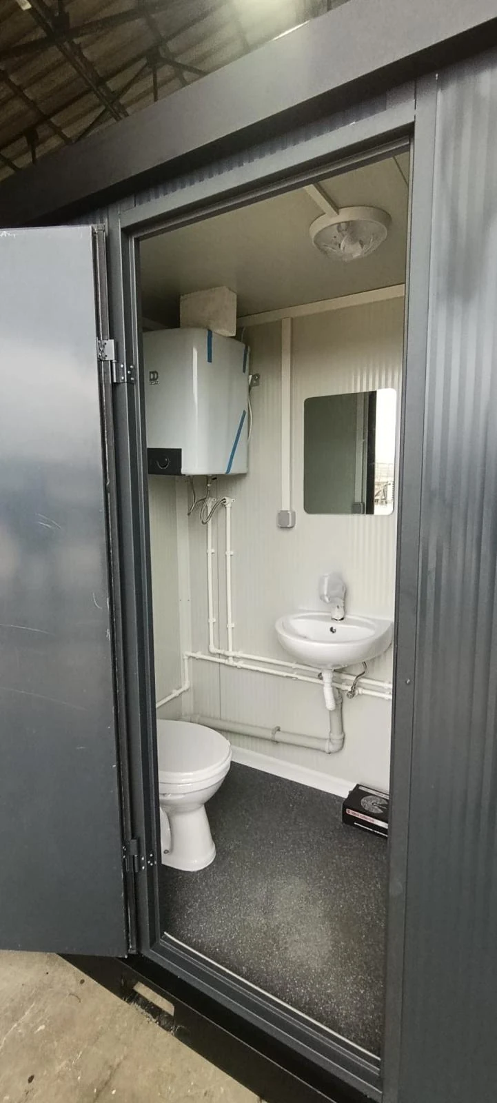 Compact WC interior with washbasin, mirror, window and visible plumbing